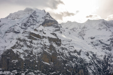 View of the Swiss mountains in winter. Eiger in clouds, Monoch and Jungfrau. Swiss alps in...