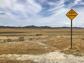 View of Utah desert on a summer day.  Snakes and scorpions warning sign. 18 wheeler truck passing by in the background.
