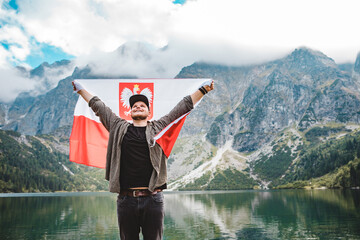 man with poland flag at eye of sea lake in tatra mountains