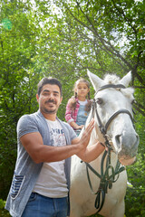 Kirov, Russia - August 07, 2020: A teenage girl, mother, father and a horse in nature among green trees