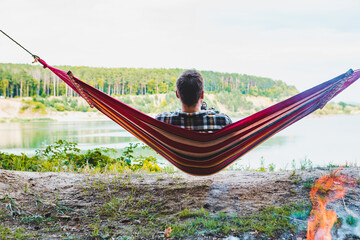 man resting on hammock and looking at lake