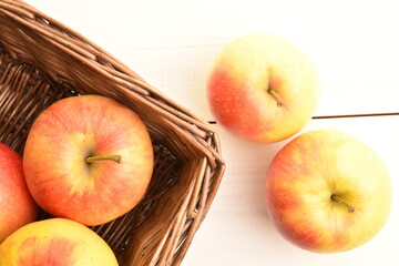 Several ripe organic, juicy, aromatic apples in a basket, close-up, on a wooden table.