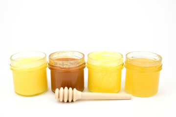 Various types of honey with a scoop lying next to it isolated on a white background.
