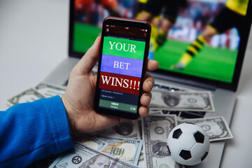 Lucky winner at football betting with phone in hand and dollar bills. Betting and gambling concept.