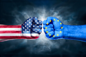 Flags of EU and USA painted on two fists on sky background. EU versus  USA trade war disputes...