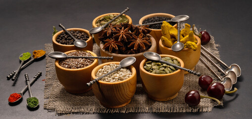 Spices and condiments in spoons and bowls for cooking on black background