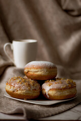 Close up on traditional polish donuts, served on Fat Thursday, selective focus, coffee cup at the background
