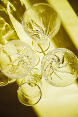 Empty glasses stand on a yellow background, top view. Sunlight is refracted through the glass.