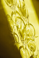 Empty glasses stand on a yellow background, top view. Sunlight is refracted through the glass.