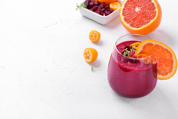 Smoothie with beet root, berries and blood orange topped with microgreen in a glass on white