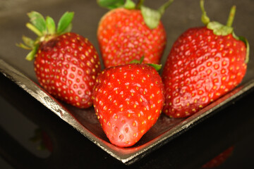 Several berries of bright red ripe organic delicious strawberries on a metal tray.