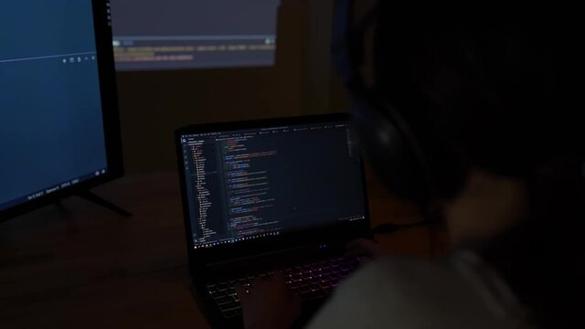 Software developer freelancer woman female in glasses work with program code C++ Java Javascript on wide displays at night Develops new web desktop mobile application or framework Projector background