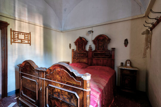 November 2020, Italy. Antique carved wooden bed in a bedroom of an abandoned house in Northern Italy. Urbex in Italy