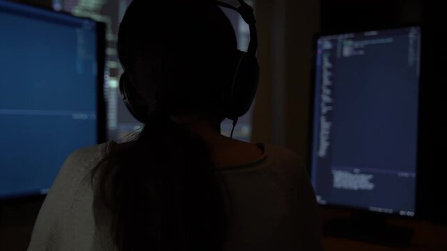 Software developer freelancer woman female work with program code C ++, Java, JavaScript on multiple displays on workplace at night. Programmer girl develops web desktop mobile application, framework.
