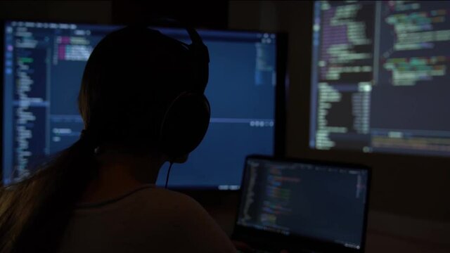 Software developer freelancer woman female in glasses work with program code C++ Java Javascript on wide displays at night Develops new web desktop mobile application or framework Projector background