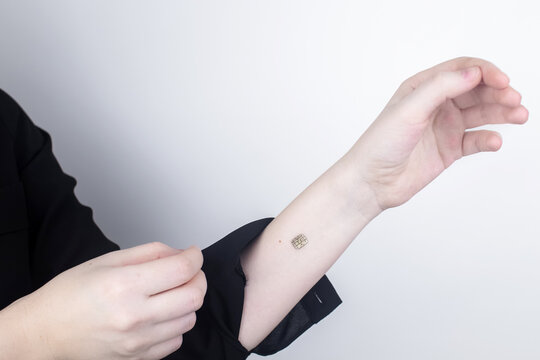 The woman shows his hand with a chip implanted. The concept of chipping and implantation of electronic technologies into the human body. Cybernetics and the nanofuture. Cyberpunk - Powered by Adobe