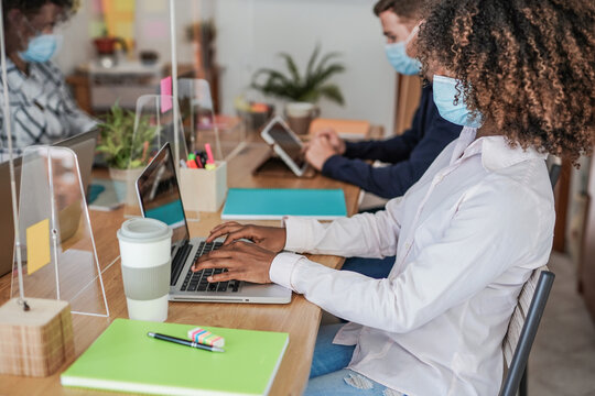 Multiracial coworking staff in office with dividers and face masks for coronavirus outbreak