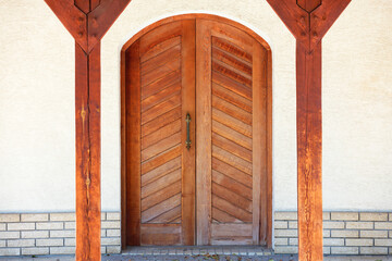 Front entrance wooden doors of a Ukrainian village hut with a massive copper handle and two symmetrical wooden supports.