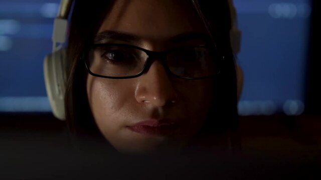 Portrait of software developer freelancer woman female in glasses work with program code on laptop at workplace at night. Programmer girl develops web desktop mobile application. Projector background.