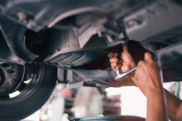 Mid adult mechanic repairing undercarriage of a car in auto repair shop.