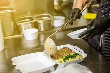 Chef preparing dish to a box in the restaurant for food delivery service to home, online ordering