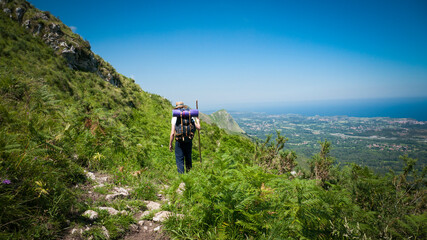 Caminante de peregrino con mochila, sombrero de paja y palo de madera por camino entre montañas en...