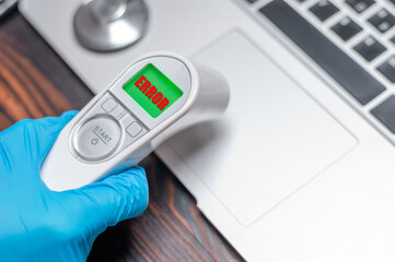The technician applies an infrared thermometer to the laptop panel. Analysis of problems. Computer...