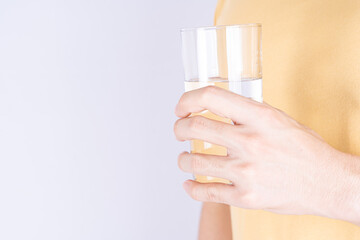 Man holding glass of water isolated grey background. Clean drinking water in clear glass.