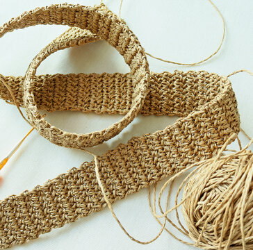 Photo of crocheting of waistband from raffia on fabric background