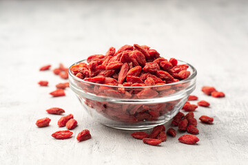 Dry goji berries in glass bowl on concrete background