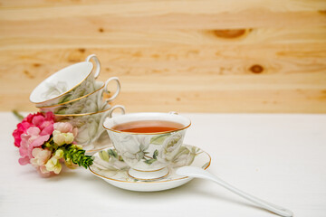 Porcelain cup of herbal tea and flowers on light background. Selective focus, soft focus. copy space