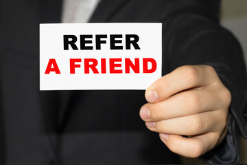Card with text REFER A FRIEND on hand. You can use in business, marketing and other concepts. Messege of the day.