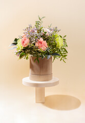Eco friendly monochrome composition with flowers bouquet standing on wooden stands of different forms on beige.