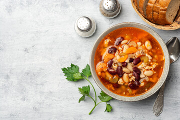 Bean soup with bacon, carrot, celery and onion in bowl on concrete background