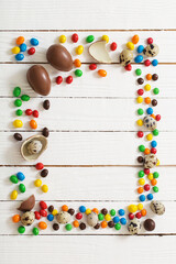 Easter chocolate eggs and candies on white wooden background