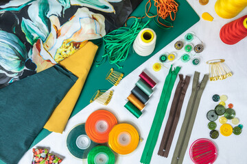 Dressmaker's workspace. Professional sewing material. Table with fabrics, elastic, safety pins, buttons, ribbons, zips, threads and needles. Top view