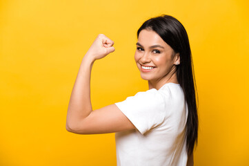 Young caucasian woman in a white t-shirt showing her strength by showing her hand while standing...