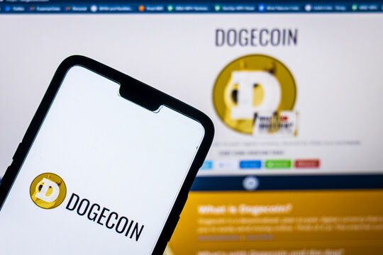 Dogecoin logo on a smartphone aganist dogecoin website on a pc in the background. Dogecoin's value has spiked after Elon Musk tweeted multiple times about it.
