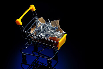 Steel screws lie on craft paper in a small shopping cart. Advertising photo for a supplier of fasteners with space to copy. Dark background