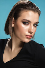 Naklejka premium Magazine style. Portrait of young female fashion model isolated on blue studio background. Beautiful caucasian woman with trendy make-up and well-kept skin. Style and beauty concept. Close up.