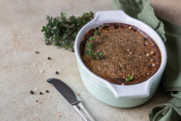 Baked chicken or turkey liver pate or souffle in ceramic mold with thyme, stone background.