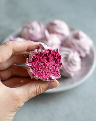 A woman's hand in a pink glove holds a homemade marshmallow. Vertical photo.