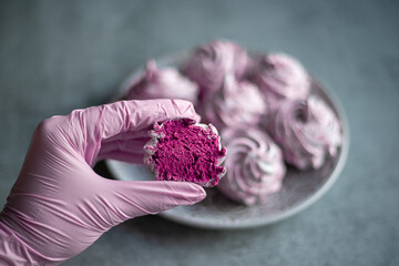 A woman's hand in a pink glove holds a homemade marshmallow