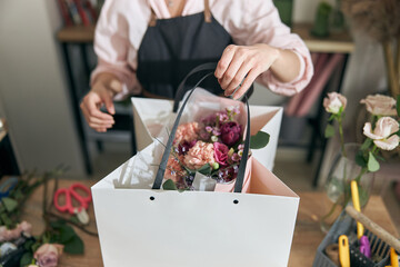 Professional florist young woman is doing bouquets at flower shop
