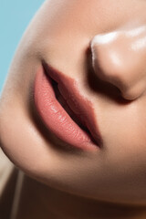 Lips. Close up of young female fashion model's face isolated on blue studio background. Beautiful caucasian woman with trendy make-up and well-kept skin. Style and beauty concept.