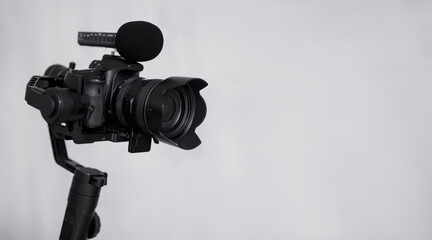 modern dslr camera on 3-axis gimbal stabilizer with microphone over gray background