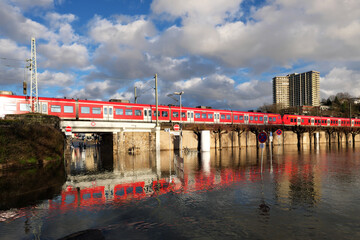 Fototapeta premium Hochwassser am Rhein an Bahntrasse in Vallendar bei Koblenz mit vorbeifahrendem Zug im Februar 2021 - Stockfoto