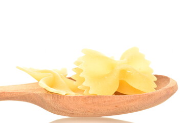 Light yellow uncooked pasta, in the shape of a butterfly, with a wooden spoon, close-up, isolated on white.