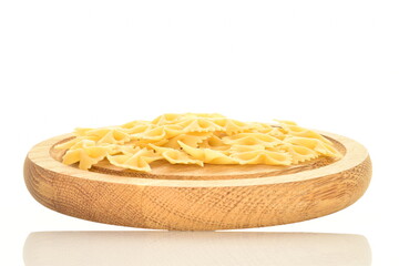 Light yellow uncooked pasta, butterfly shaped, on a wooden tray, close-up, isolated on white.