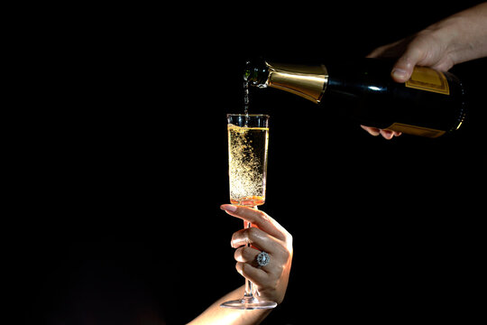 Close up of man and woman hands celebrating Valentine's Day with champagne. . High quality photo